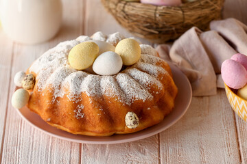 Plate with tasty Easter cake and painted eggs on white wooden table