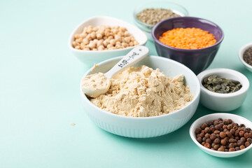 Healthy Dry Pea Protein Powder and Plant Based Protein Food (legumes, lentils, beans, seeds) on Blue Green Background.