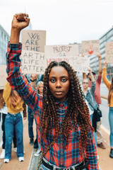 portrait of african american young woman with raised fist at street demonstration for climate -...