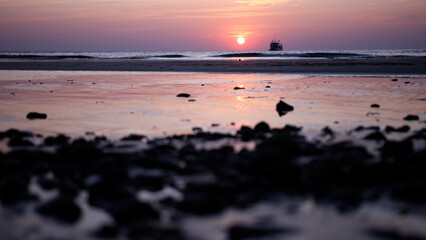 Fototapeta na wymiar Beautiful view sunset over sea, ocean waves crashing on a stones beach