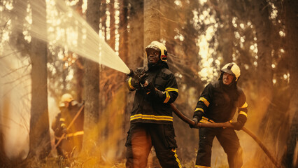 Fototapeta premium Portrait of a Brave Professional African Firefighter Using a Firehose to Fight a Raging Dangerous Forest Fire. Experienced Black Fireman Skillfully Manages the High-Pressure Water and Stays Safe.