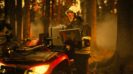 Brave Skillful Firefighter Standing Next to an ATV, Using Laptop Computer in Forest with Raging...