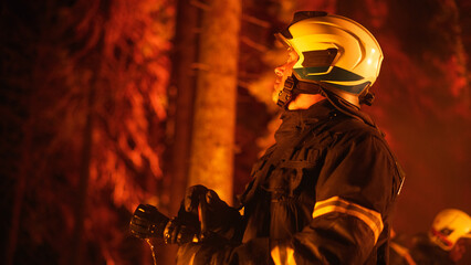 Experienced Firefighter Extinguishing a Wildland Fire Deep in the Woods. Professional in Safety Uniform and Helmet Holding Fire Hose, Looking Up, Assuming and Calculating the Direction of Wind.