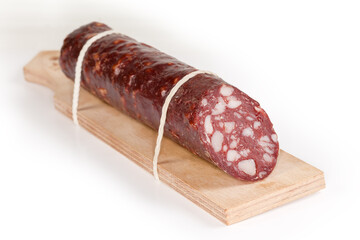Smoked cured sausage on special cutting board on white surface