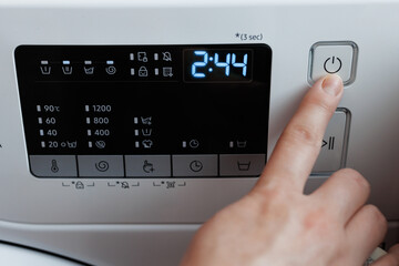 Hand turning on and off the switch of the washing machine. Person's finger turning on and off the...