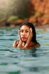 Portrait of serene looking attractive young black female posing in bikini in water. African model posing in the sea. Multiracial woman posing at the beach in ocean. Fashion portrait of black woman
