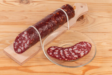 Partly sliced smoked-cured sausage on the rustic table
