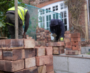 Two construction workers laying bricks as part of a renovation of an Edwardian suburban house in north London, UK