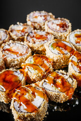 hot sushi roll tempura with eel shrimp crab salmon cream cheese cucumber avocado unagi on a black mirror background