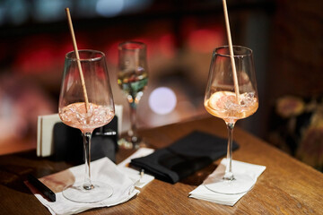half-empty glasses with a cocktail, with ice and a slice of orange are on the table in the bar. Two half-empty glasses with ice and an orange slice stand on a table in a bar