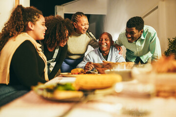 Happy african family eating dinner together at home terrace outdoor - Soft focus on senior woman...