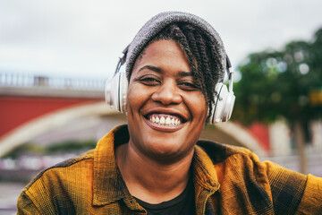Happy african american woman listening playlist music outdoor - Focus on face