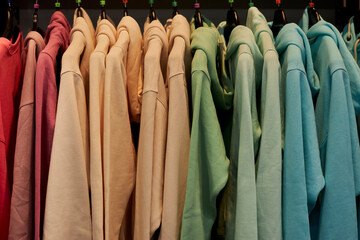 multi-colored sweatshirts on hangers in the store. Bright colorful sweatshirts hang in a fashion...