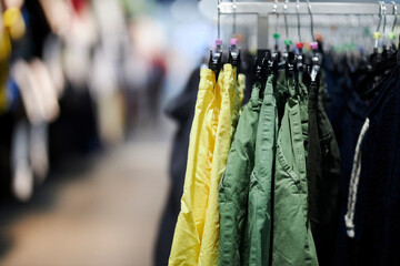 multi-colored men's and women's trousers on hangers in a clothing store. colorful pants store, new clothes during shopping, colorful men's and women's pants on hangers in a retail store