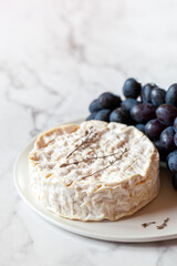 Camambert french soft cheese served with grapes, decorated with thyme branches