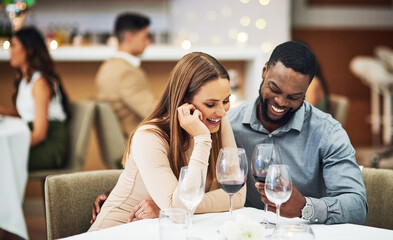 Date, laughing and interracial couple with wine in fine dining, luxury restaurant or valentines celebration together. Funny black man, happy woman and alcohol glasses for romance, rich or anniversary - Powered by Adobe