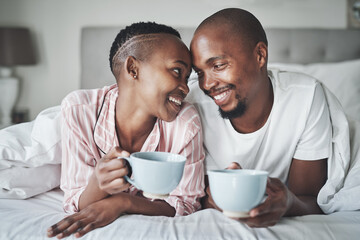 Coffee, bedroom and morning with a black couple together on a bed in their home to relax on the...