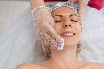 Сosmetologist prepares client skin for procedure in beauty salon