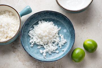 Blue bowls with cooked white rice on a light-beige stone background, horizontal shot, high angle view