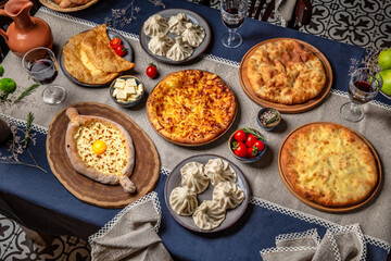 Traditional Georgian Adjara khachapuri, manti and Kolkh khachapuri on the table. Food Table Celebration Delicious Party Meal Concept. 