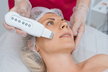 Close-up of beautiful womans face during ultrasonic peel skin procedure at spa salon. Ultrasonic...