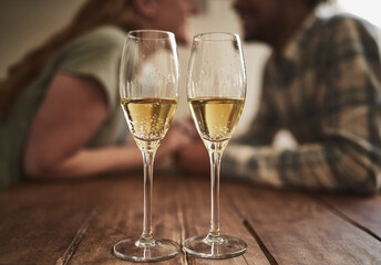 Champagne, glass and love on valentines day with a couple kissing in the background of a restaurant for romance. Alcohol, drink or dating with a man and woman sharing a kiss on a romantic date