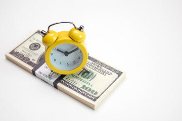Bundle of dollars and yellow Alarm clock on white background
