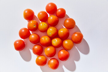 red cherry tomatoes on a white background, hard light, shadows 