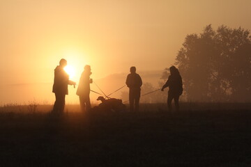 silhouette of people walking with a dogs at sunrise