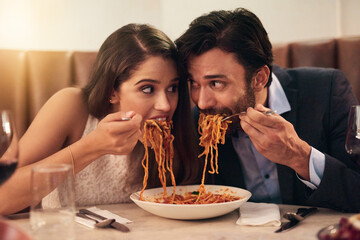 Hungry, restaurant and couple eating spaghetti for love, crazy fun and sharing plate on valentines date celebration. Happy people with pasta food for anniversary, dinner or fine dining experience