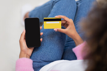 Top view of black woman using phone and credit card