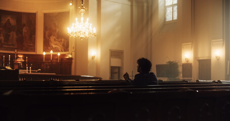 Young Christian Man Sits Piously in Majestic Church, with Folded Hands He Seeks Guidance From Faith...