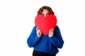 Portrait of young woman wearing blue pullover sweater isolated over white background covering mouth with heart shaped card looking camera smiling cheerful close-up.