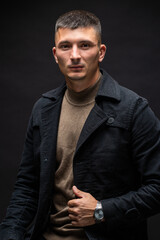 Young successful stylish man. Classical portrait of a businessman dressed in a jacket with a watch on his hand.