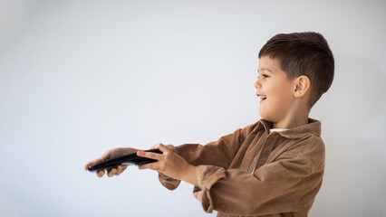 Smiling caucasian little child with remote control switches channels on TV set, chooses cartoon on...