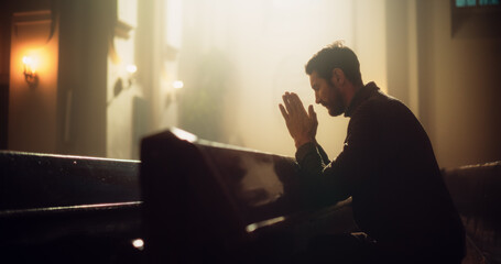 Young Christian Man Sits Piously in Majestic Church, with Folded Hands After a Cross Prayer. He...