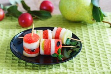 fresh fruit canape in a black plate on a green napkin