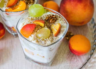 Fruit salad with yogurt and walnuts in glass bowl, healthy food concept