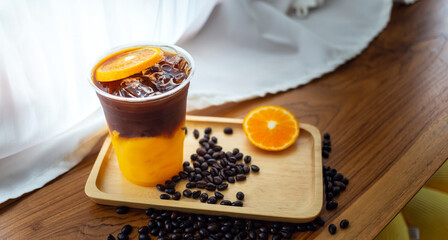 iced coffee drink menu Orange Americano with fresh orange fruit mixed in a plastic cup On the wooden bar counter in the cafe