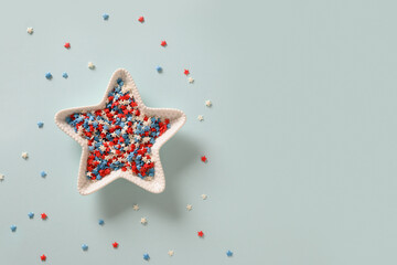 USA Independence Day concept. Red, white and blue star confetti in plate shape of star on blue...