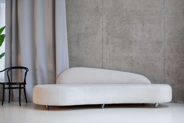 Modern interior with a white velor sofa against a concrete wall. Photo studio.