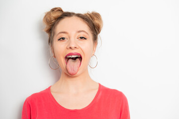 Young caucasian woman with two hair bundles wearing braces showing tongue 