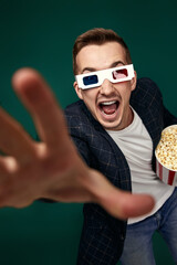 Obraz premium man in 3d glasses holding a big bucket of popcorns
