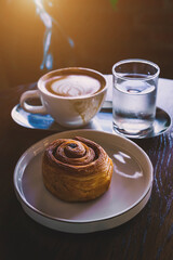 Hot coffee latte with latte art milk foam in cup mug and Homemade Raisin Danish white plate on wood desk on top view. As breakfast In a coffee shop at the cafe,during business work.