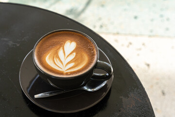 Hot coffee latte with latte art milk foam in cup mug on black wood desk on top view. As breakfast In a coffee shop at the cafe,during business work concept
