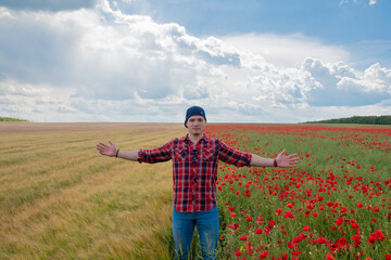 Fototapeta na wymiar Young Man wearing Red for Valentines day, posing in Flower Field with Poppies. Love and Romance