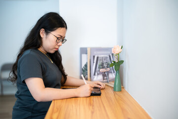 Obraz na płótnie Canvas Portrait asian freelance people business female wearing glasses stylish hipster Draw or taking note on digital tablet with electronic pen for browsing internet, chatting and blogging in coffee shop.