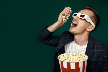 guy in 3d glasses eating popcorn on pink background © Rychko Yevhen