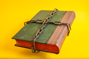 Old green bible with red pages tied with thick chains
