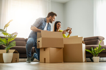 Smiling couple unpaking boxes in new home - 569170921